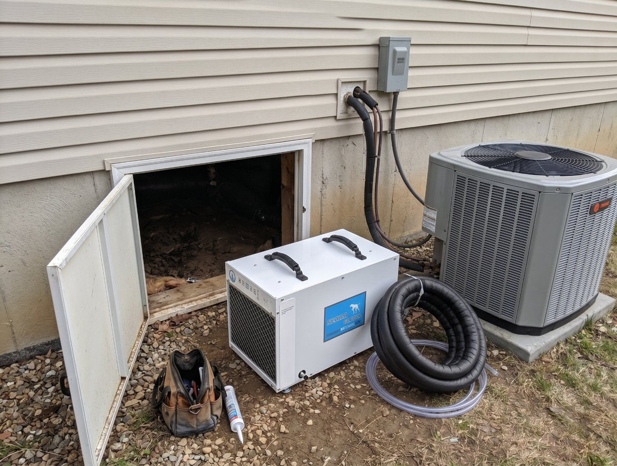 Dehumidifier outside a crawl space entrance with next to an ac unit