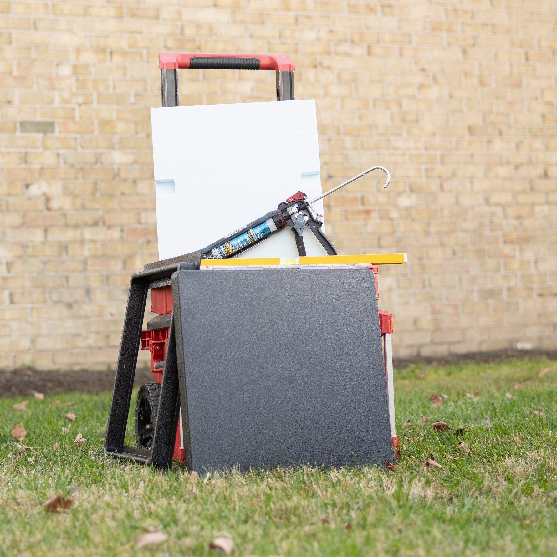 The frame, insulation, and cover of a crawl space door with silicone adhesive propped on a toolbox