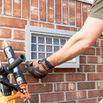 Person installing vent into brick foundation with silicon adhesive