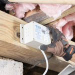 Hand installing a electrical outlet box into wooden framing with insulation.